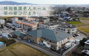 特別養護老人ホームの建物全景。周囲の田園風景と施設の配置が見える空撮写真。